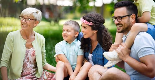 Multigenerational family spending time together outdoors, representing security and long-term peace of mind.