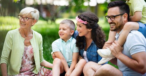 Multigenerational family spending time together outdoors, representing security and long-term peace of mind.